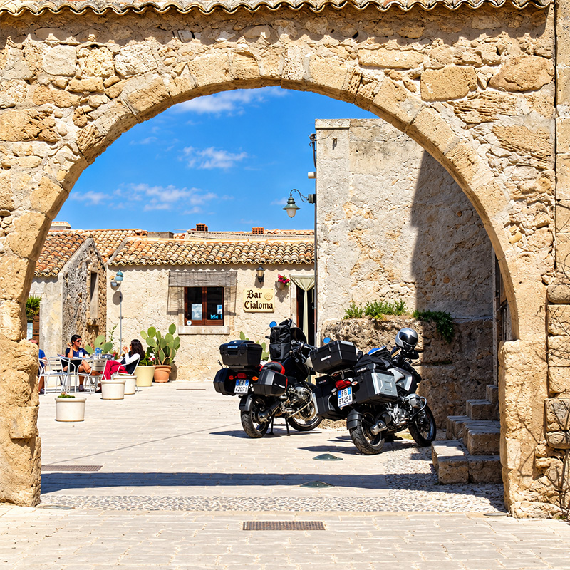 A group of motorcyclists travelling between mountains and lakes